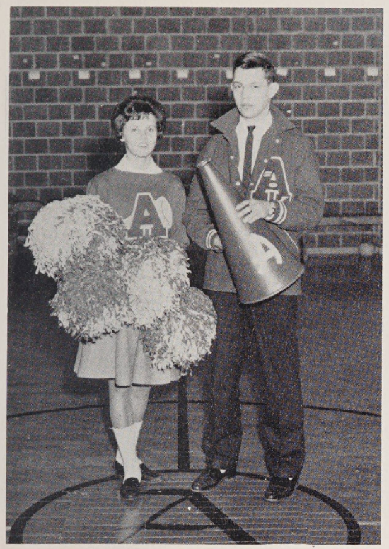 A cheerleader holding pom poms, Betty Dare Funderburk, is on the left, and Les Scott stands on the right holding a cheering horn. 